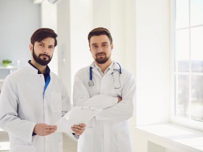 Zwei Ärzte stehen selbstbewusst in einer Praxis