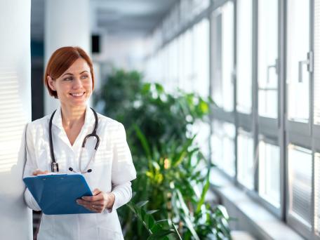 Ärztin in einem Krankenhaus mit Klemmbrett lächelt