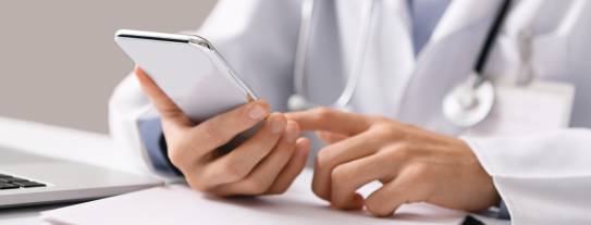 Arzt scrollt am Handy