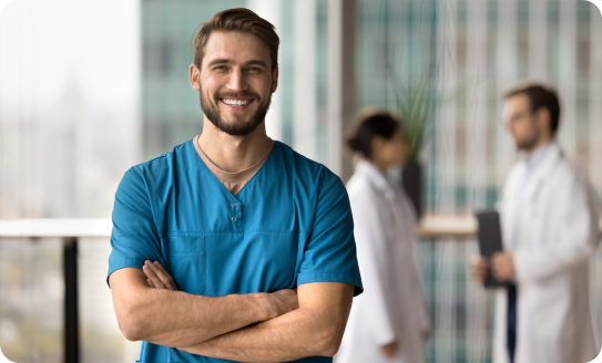 Arzt lächelt zufrieden mit verschränkten Armen und Krankenhaus im unscharf im Hintergrund