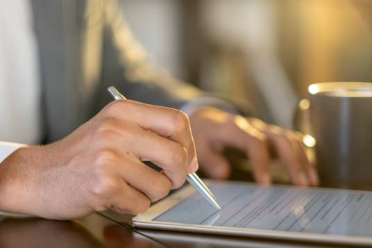 Person füllt Formular mit Stift am Tablet aus